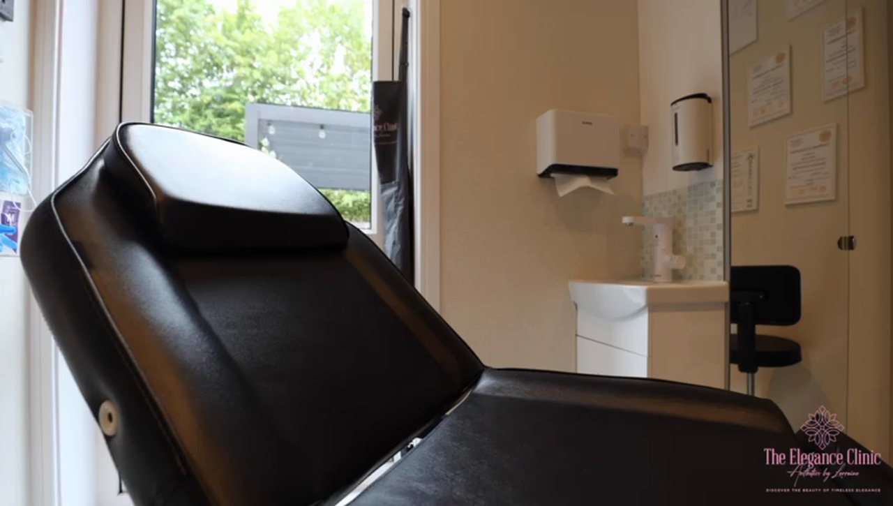 The private treatment room at The Elegance Clinic — treatment couch, clinical hand-wash station and certificates on display